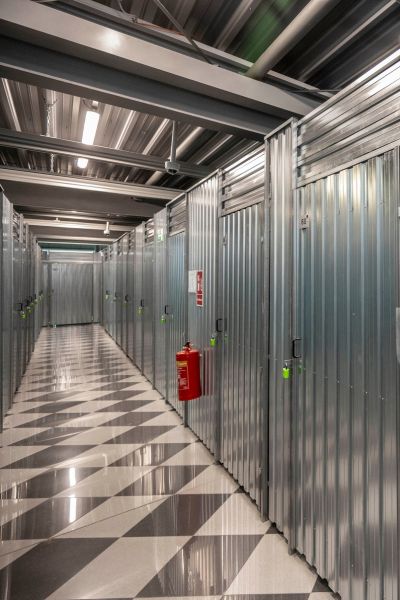 Beleuchteter Gang mit abschließbaren Lagerabteilen und Feuerlöscher bei Storebox Aalen